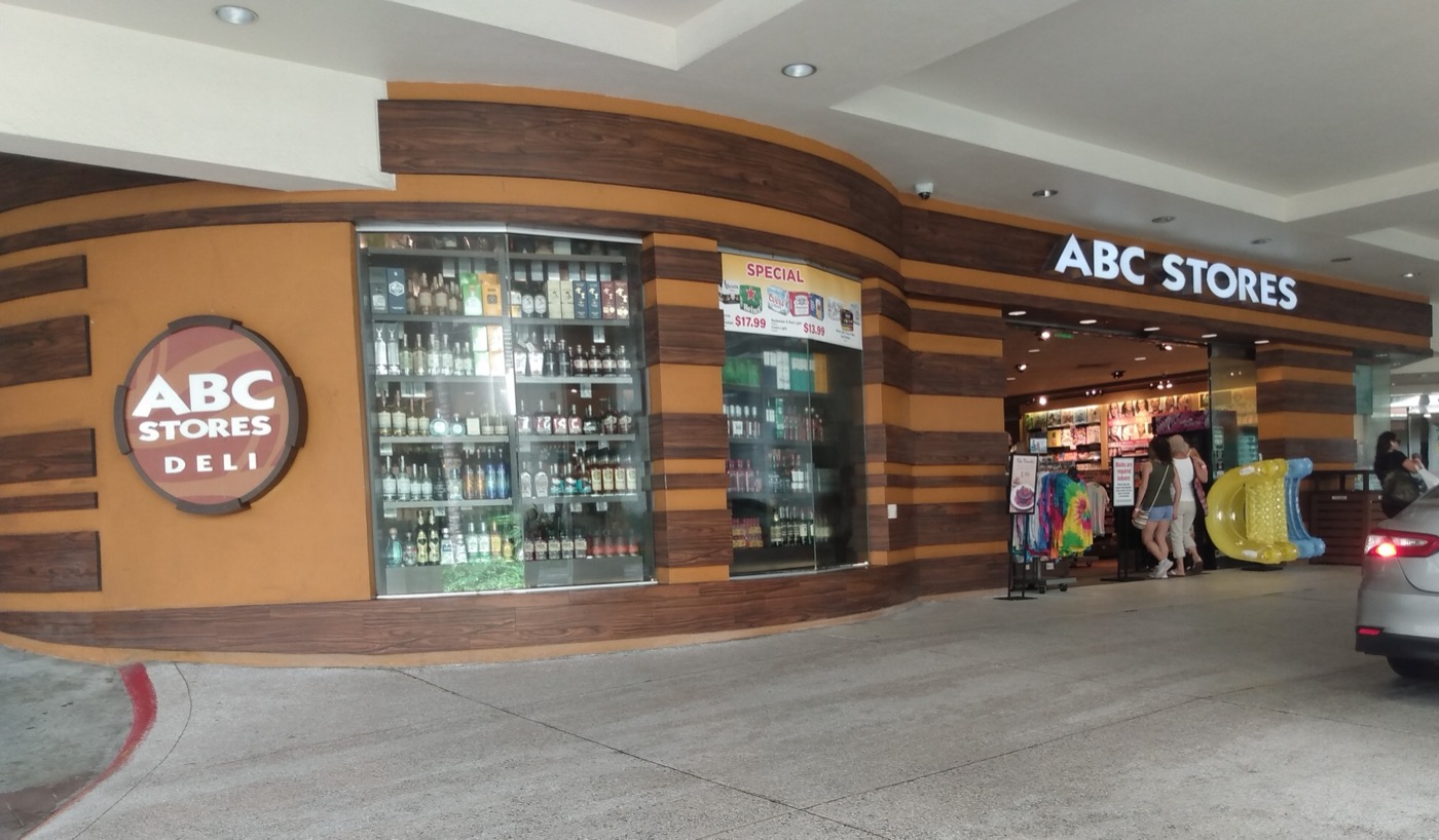 Exterior of an ABC Store in Waikiki with red and white signage and tropical merchandise visible.