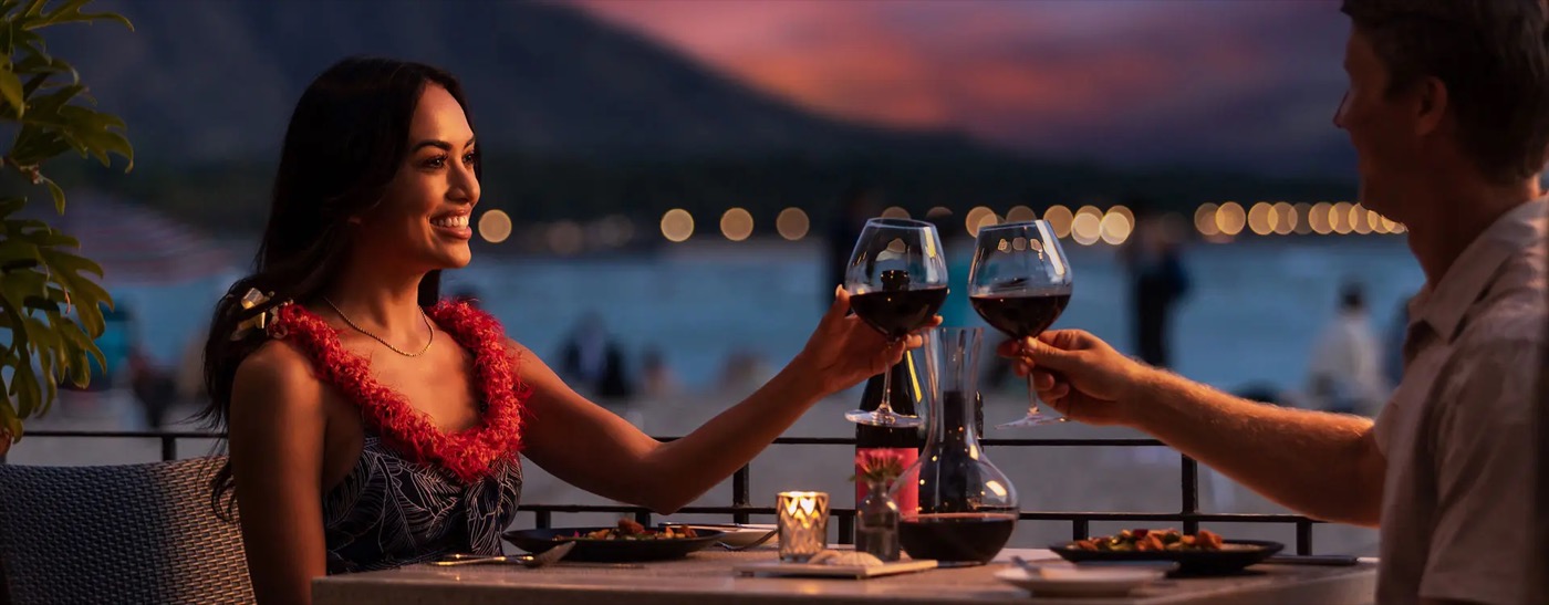Beachfront dining tables at Azure beneath the Royal Hawaiian's Spanish-Moorish arches at sunset.