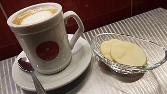 A cortado in a glass cup, the signature pour at The Curb Kaimuki.